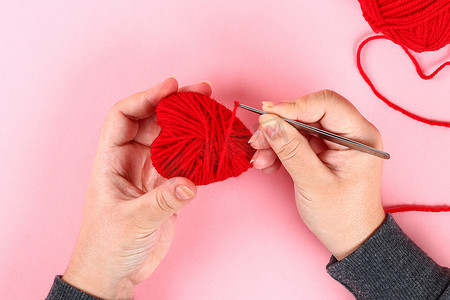 红色手工制作的多毛心由纸板制成, 纱线上有粉红色的背景。情人节、白天爱情、2月14日的概念的礼物创意。一步一步。工艺工艺。情人节贺卡