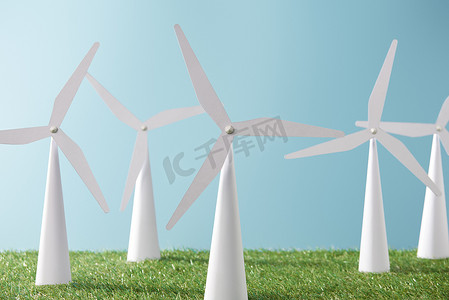 白色风车模型在蓝色背景和绿色草  