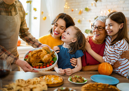 感恩节快乐！秋天的宴会。一家人坐在桌旁庆祝节日.祖父母、母亲、父亲和子女。传统的晚餐.