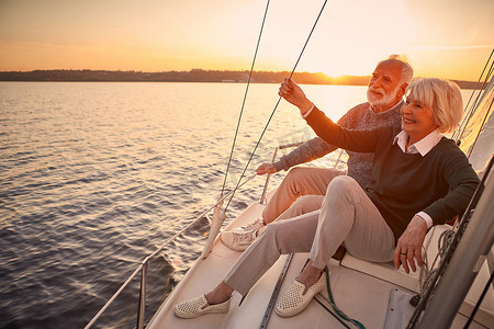 51畅游摄影照片_享受奢侈的生活。美丽而快乐的老夫妇坠入爱河，在夕阳西下漂浮在帆船或游艇甲板上，欣赏着迷人的夜景