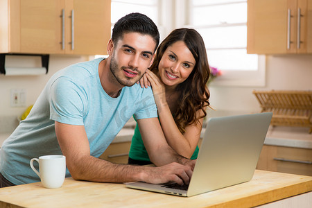 Husband and wife couple sharing a computer laptop social network laughing smiling searching for funny content with coffee