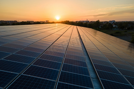 蓝色光电太阳能电池板安装在建筑物的屋顶上，以便在日落时产生清洁的生态电力。可再生能源概念的生产.