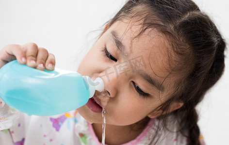 被水流冲洗的刷子摄影照片_年轻的亚裔女孩生病的孩子用鼻腔冲洗鼻子