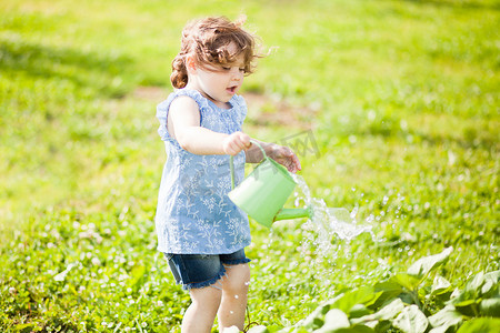  小女孩用喷壶在花园里
