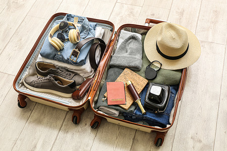 male摄影照片_Suitcase with male accessories for travelling on white wooden background