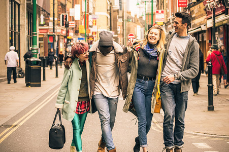 快乐的多种族朋友在肖尔迪奇的砖车道漫步伦敦-与多元文化的年轻人的友谊概念冬季衣服有乐趣在一起-软焦点与温暖的对比过滤器