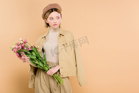 时髦的女人拿着花束与花隔离在米色 