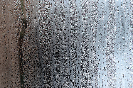 透明灰色背景摄影照片_质地的一滴雨在玻璃湿透明的背景上。灰色色调