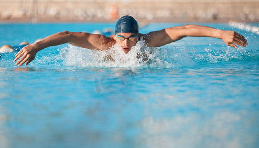a handsome young male athlete swimming in an olympic-sized pool.