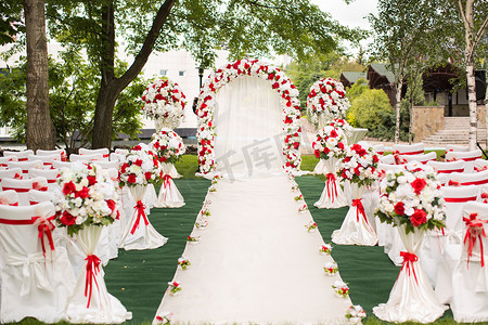 婚礼在户外举行。红花装饰的婚礼拱门.