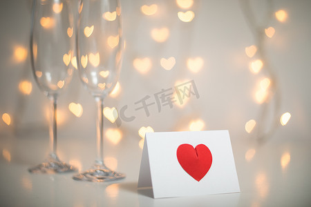 浪漫的留言, 上面有红色的3d 心, 还有带有眼镜和童话般的灯光弦的香槟酒, 背景是心
