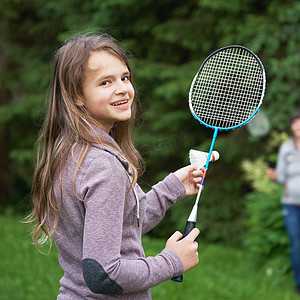 青少年女孩与羽毛球拍和穿梭球微笑的相机