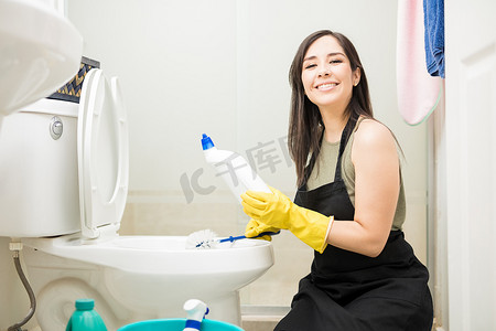 酒店女服务员摄影照片_可爱的女服务员清洁酒店卫生间卫生间的洗手间与消毒剂和刷子