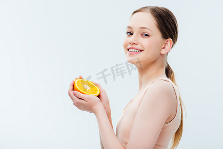 快乐微笑的青少年拿着橙色的半孤立在灰色