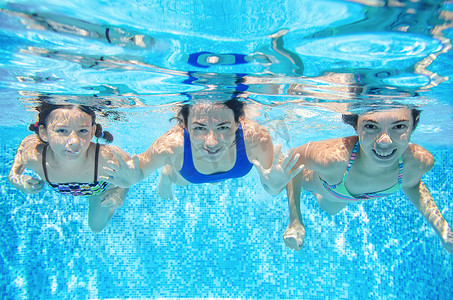 家庭游泳在游泳池水下，快乐活跃的母亲和孩子在水下的乐趣，健身和运动与孩子们在暑假度假
