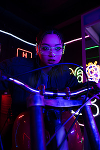 young asian woman in sunglasses riding motorbike near neon sign 