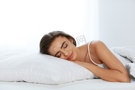 枕头摄影照片_白色床上用品。睡在床垫上的女人, 床上柔软的枕头。高分辨率.