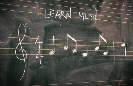 用白色粉笔写在黑板上的随机音乐音符。学习或教授音乐概念.