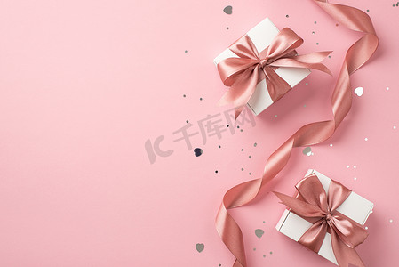 Top view photo of white gift boxes with pink bows curly ribbon silver sequins and heart shaped confetti on isolated pastel pink background with copyspace