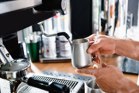 剪影咖啡杯摄影照片_咖啡豆在咖啡机蒸锅附近盛放金属牛奶杯的剪影