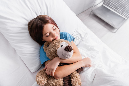 与泰迪熊睡在医院病床上的快乐女孩的头像