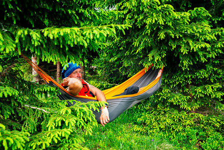 冒险家放松在吊床上的绿山草甸之间的冷杉树和梦想。史诗般的旅行在山上.