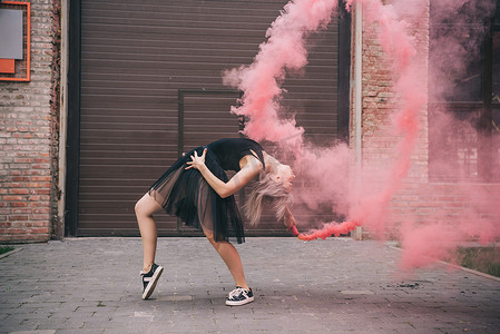 跳舞烟雾摄影照片_灵活的女孩跳舞在粉红色烟雾在城市街道  