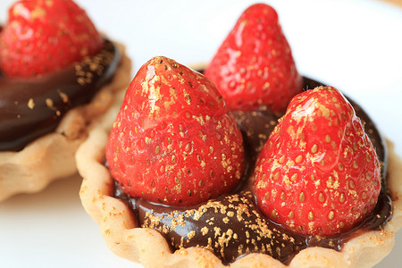 白草莓摄影照片_用新鲜草莓和用白盘盛放的可食用金粉做的巧克力馅饼特写