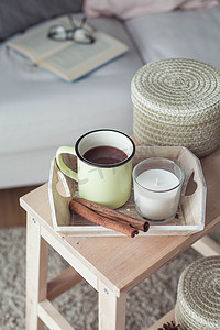 家居装饰。一个木制床头柜, 一张沙发, 一根棉花, 一杯热咖啡, 一个针织格子。温暖的房子。秋天.舒适.房子.书和眼镜。内部.