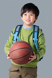小学体育锻炼摄影照片_抱着篮球的小男孩