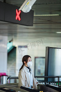 地铁戴口罩摄影照片_戴口罩的年轻女人走进地铁站