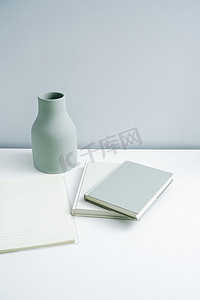 简约的书本笔记本和平平的花瓶放在桌上.非白色空间的高级家具 