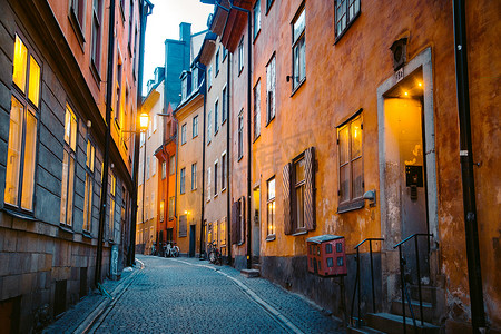 黄昏小巷摄影照片_在瑞典斯德哥尔摩市中心的黄昏时分，斯德哥尔摩历史名城甘姆拉斯坦（旧城）美丽的小巷里，传统房屋的景观在黄昏时分闪烁着光芒