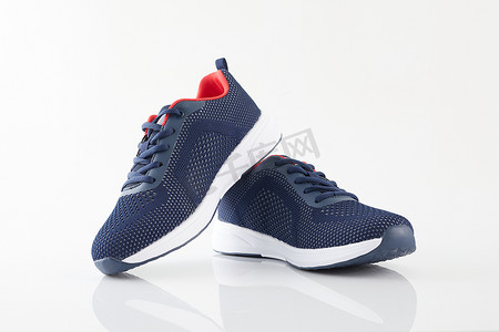 运动鞋摄影照片_一双白色背景的新无牌蓝色跑鞋或运动鞋。时尚运动鞋或健身教练.