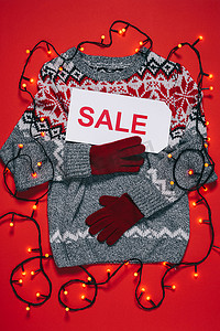 最热门的冬季毛衣, 拳击手套, 价格标签与销售字样和圣诞灯隔离在红色