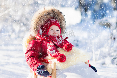 雪橇和雪为孩子们的的乐趣。婴儿在冬季公园滑雪橇.