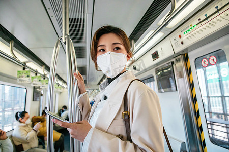 上下班摄影照片_戴口罩的年轻女人乘坐地铁