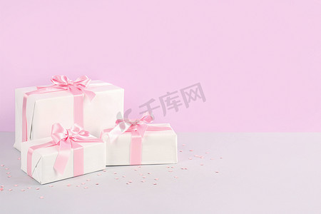粉红蝴蝶结摄影照片_粉红背景的漂亮蝴蝶结礼盒