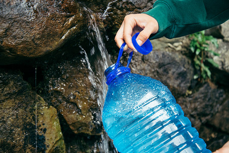 勘察水源摄影照片_女人的手填满瓶从山区水源