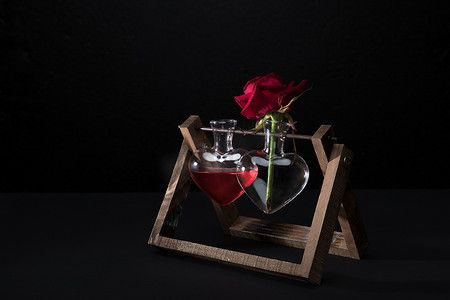 感恩在心感恩有你摄影照片_红玫瑰在心形花瓶和花瓶的爱情灵药孤立在黑色