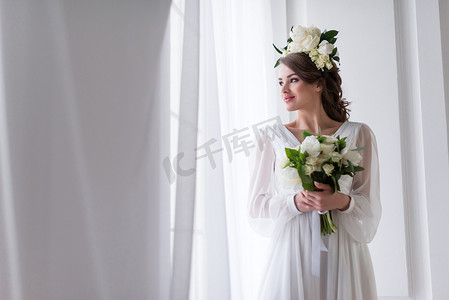 漂亮的新娘在优雅的礼服和花卉花圈举行婚礼花束 