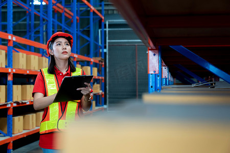 Portrait of smiling asian manager worker woman standing and order details on clipboard document for checking goods and supplies on shelves with goods background in warehouse.logistic and business export