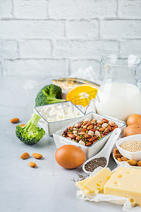 奶类豆类摄影照片_均衡的饮食营养, 健康饮食的理念。厨房桌子上富含钙、豆类、乳制品、沙丁鱼、花椰菜、起亚种子、杏仁的食物来源。复制空间背景