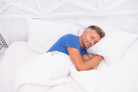 健康睡眠摄影照片_平静而成熟的男人放松。良好的睡眠是可以实现的梦想。世界睡眠日。良好和健康睡眠的好处。呼吸容易，睡个好觉。漂亮的男人在床上。睡觉的家伙在家里。需要多休息