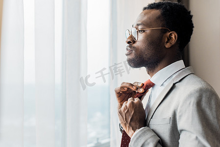 个人资料肖像非洲裔美国商人调整红色领带, 并在窗口
