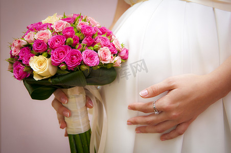 新娘捧花摄影照片_怀孕与捧花的新娘