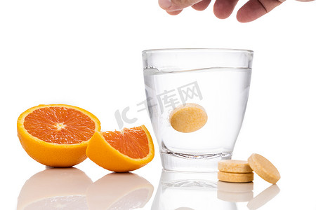 溶解摄影照片_一系列桔子味维生素C泡腾片滴在白底水杯中溶解