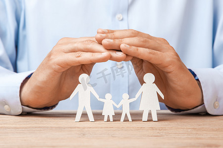 医疗或旅行保险。男人用双手从父亲、母亲、儿子和女儿手里盖住家庭。