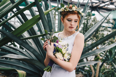 美丽温柔的年轻红发新娘举行婚礼花束在植物园里 