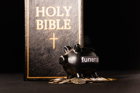带有黑色背景的硬币和圣经的储蓄罐，葬礼概念